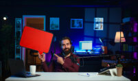A bearded man at a desk with a red board, highlighting Next Gen Streaming technology with VSEEBOX MAX and VSEE ELITE.