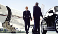 Corporate executive stepping out of a black limousine in front of a downtown office building.